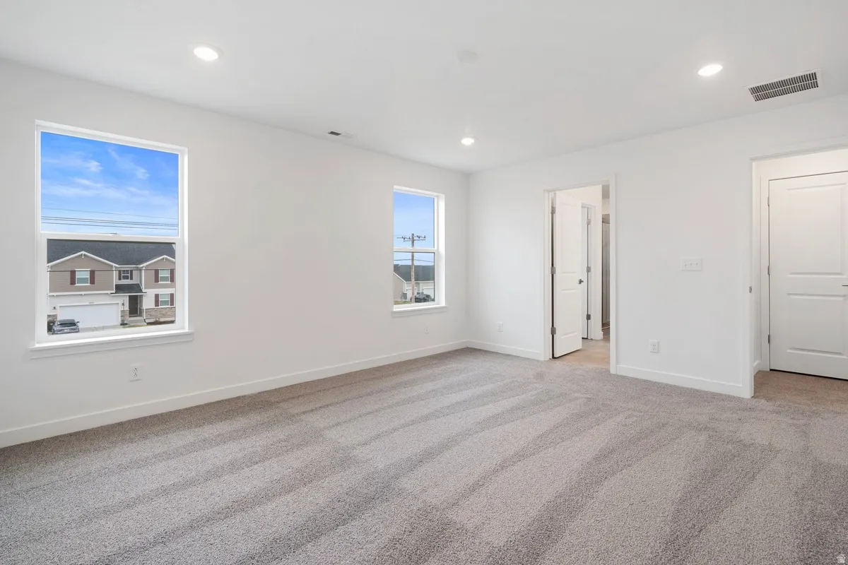 Unfurnished bedroom with light carpet and recessed lighting