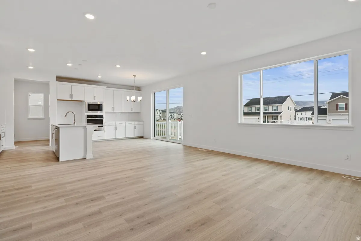Kitchen featuring white cabinets, light wood finished floors, open floor plan, hanging light fixtures, and recessed lighting