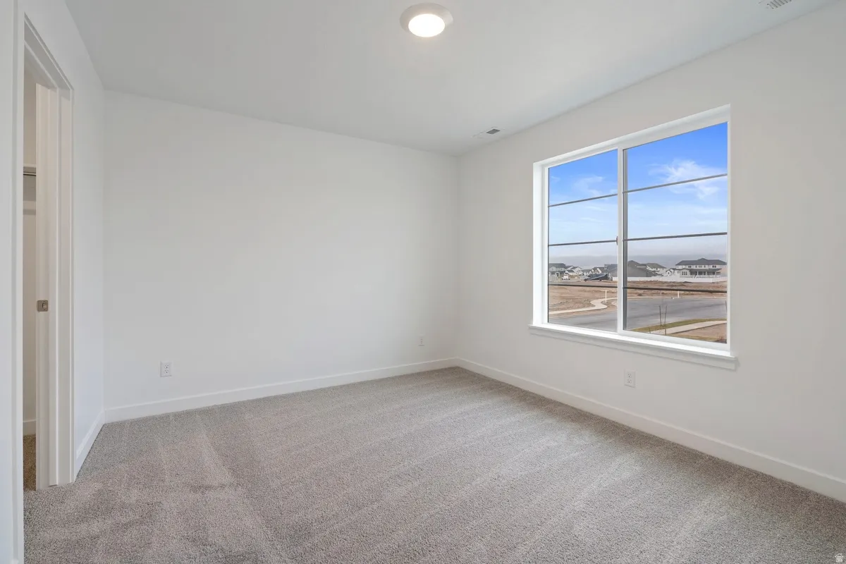 Unfurnished bedroom with light colored carpet and baseboards