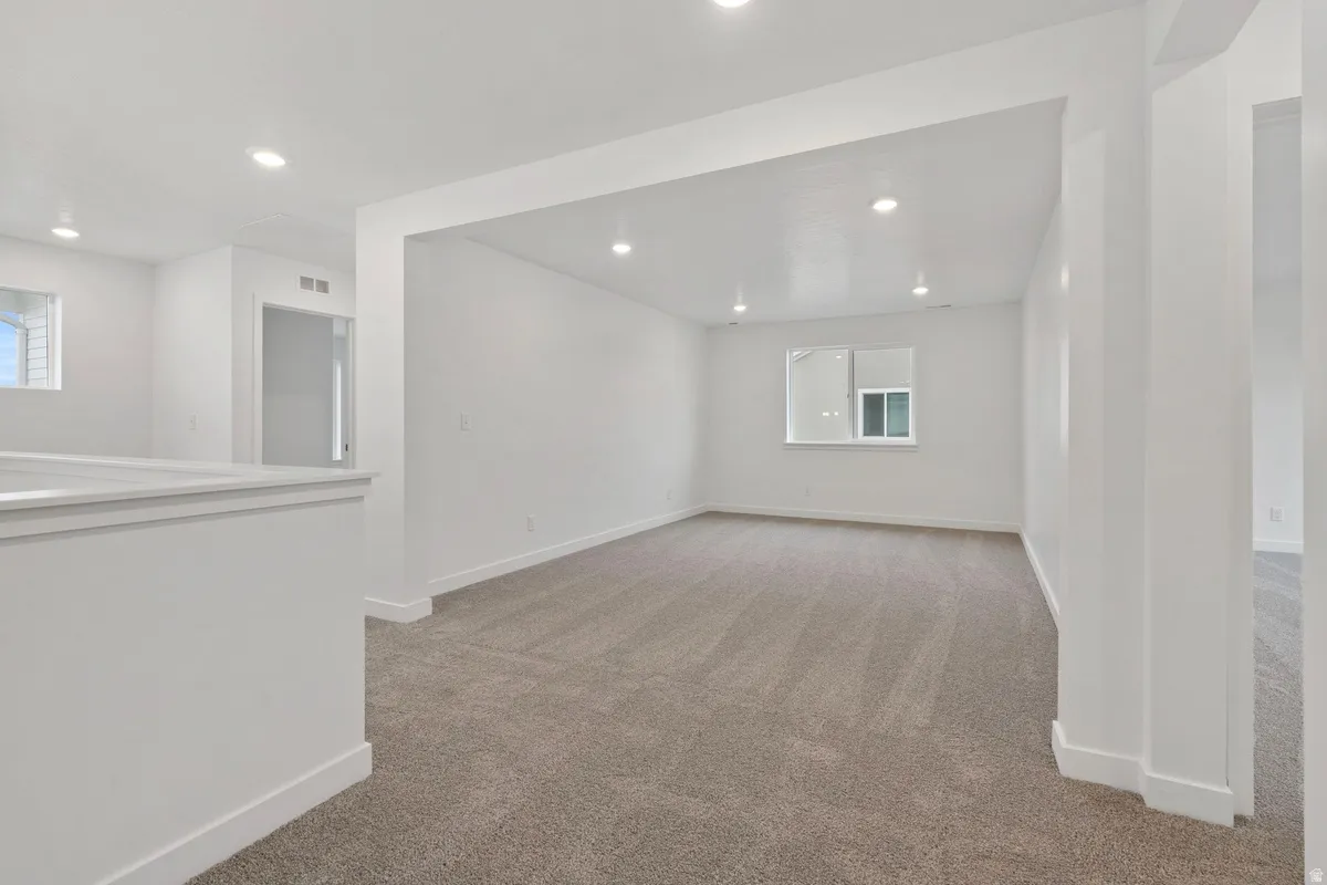 Unfurnished room featuring light colored carpet, recessed lighting, and plenty of natural light