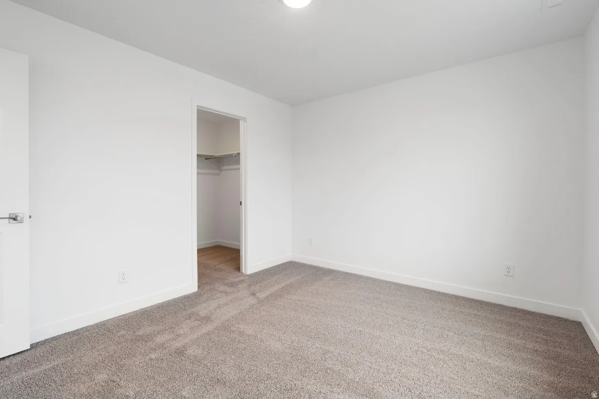 Unfurnished bedroom with carpet and a spacious closet