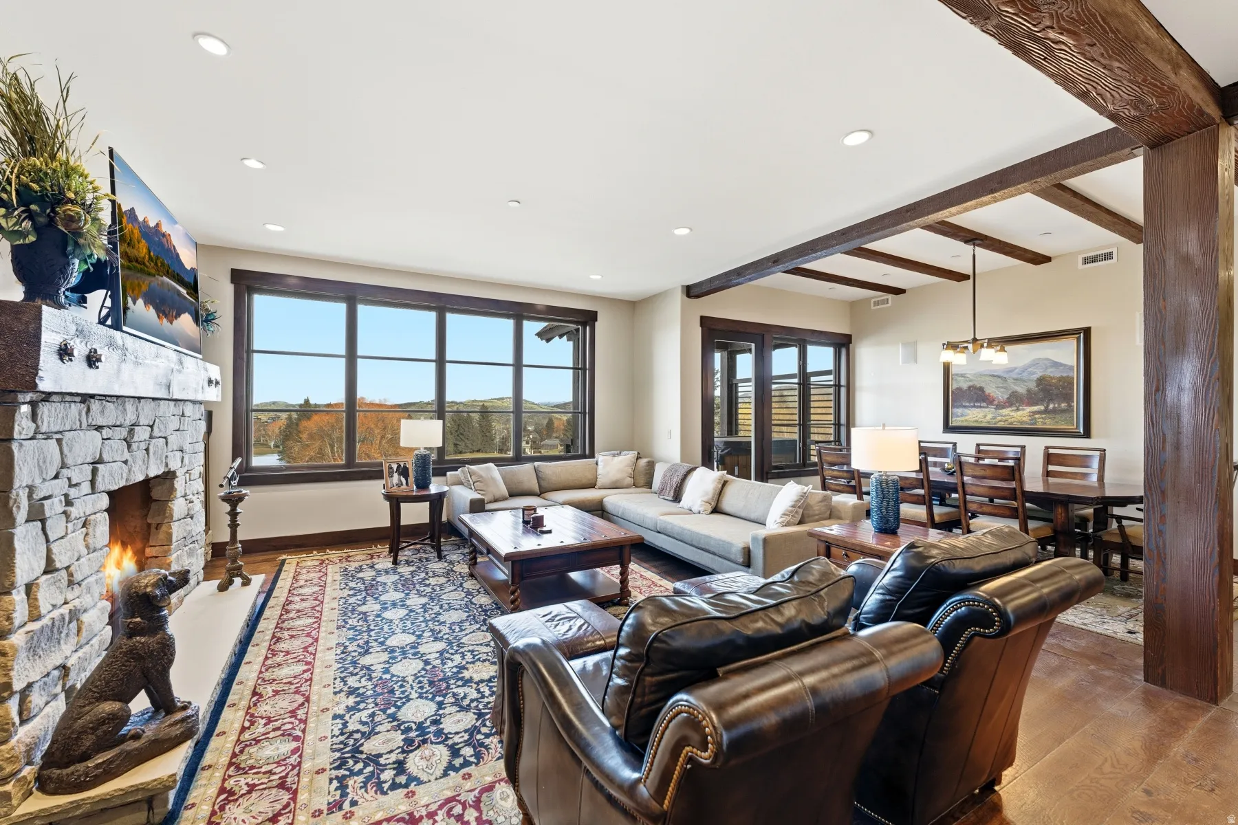 Living room featuring wood-type flooring, recessed lighting, a fireplace, beam ceiling, and a chandelier