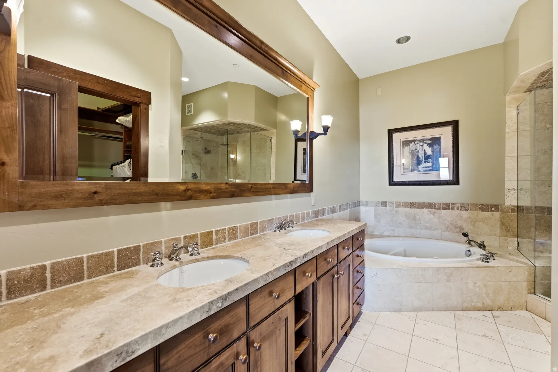Full bath featuring double vanity, a bath, a shower stall, light tile patterned flooring, and a walk in closet
