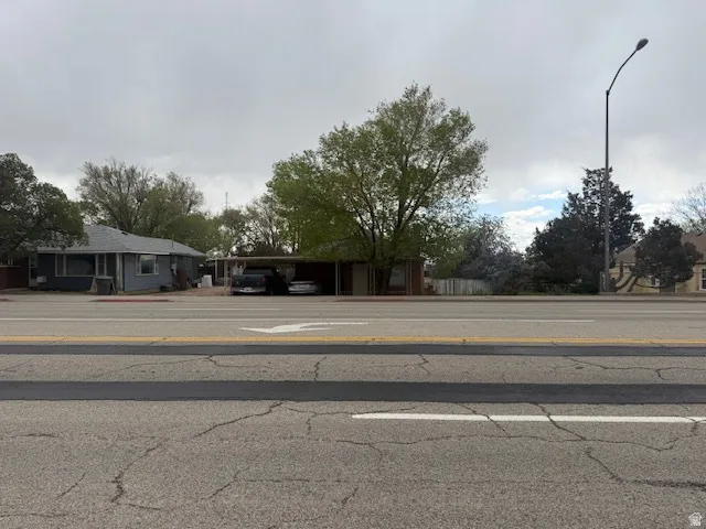 View of asphalt road featuring street lighting, curbs, and sidewalks
