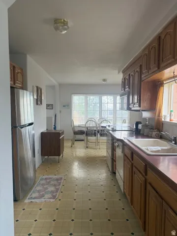 Kitchen with stainless steel appliances, plenty of natural light, light floors, and dark countertops