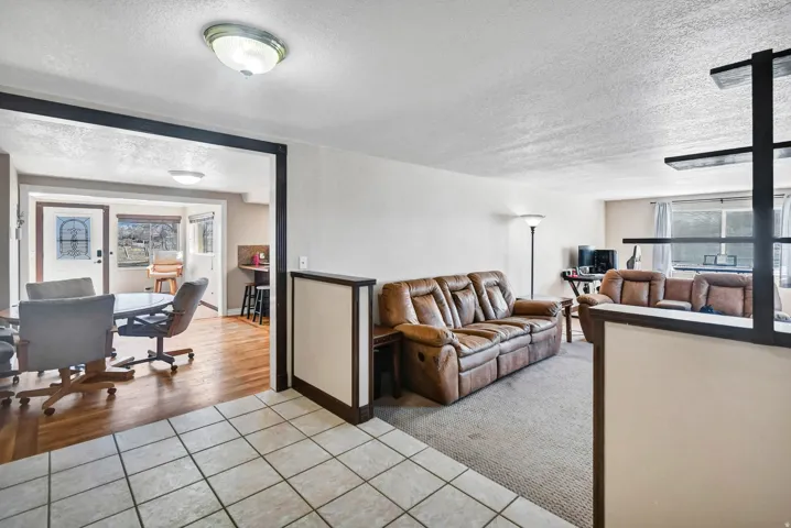 Living area featuring a textured ceiling, light tile patterned floors, light colored carpet, and an office area