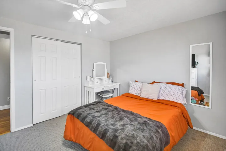 Carpeted bedroom with a closet and a ceiling fan