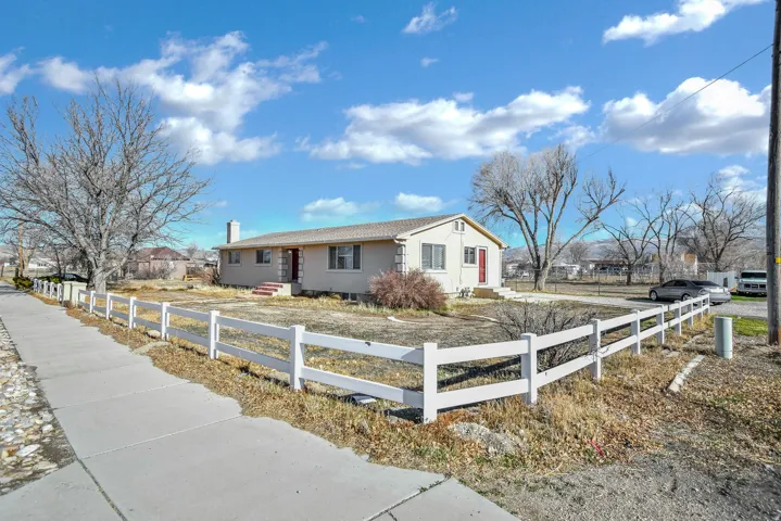 Ranch-style home with a fenced front yard, stucco siding, a chimney, and entry steps