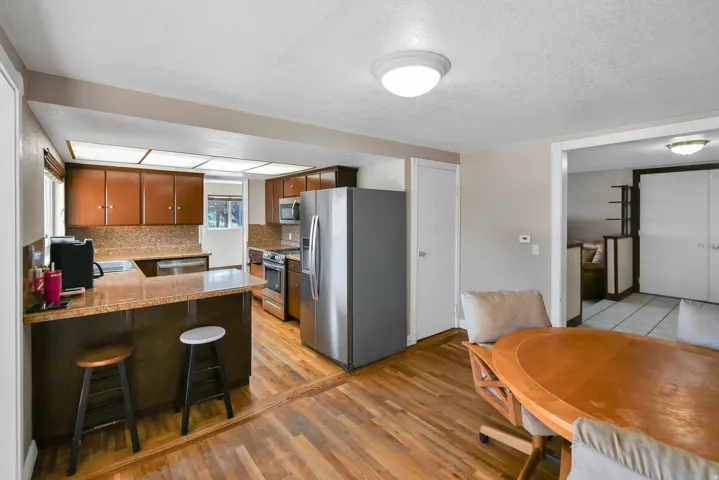 Kitchen with stainless steel appliances, brown cabinets, a kitchen breakfast bar, a peninsula, and a textured ceiling