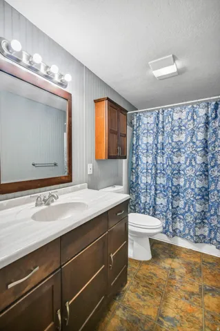 Full bath featuring vanity, a textured ceiling, and shower / tub combo