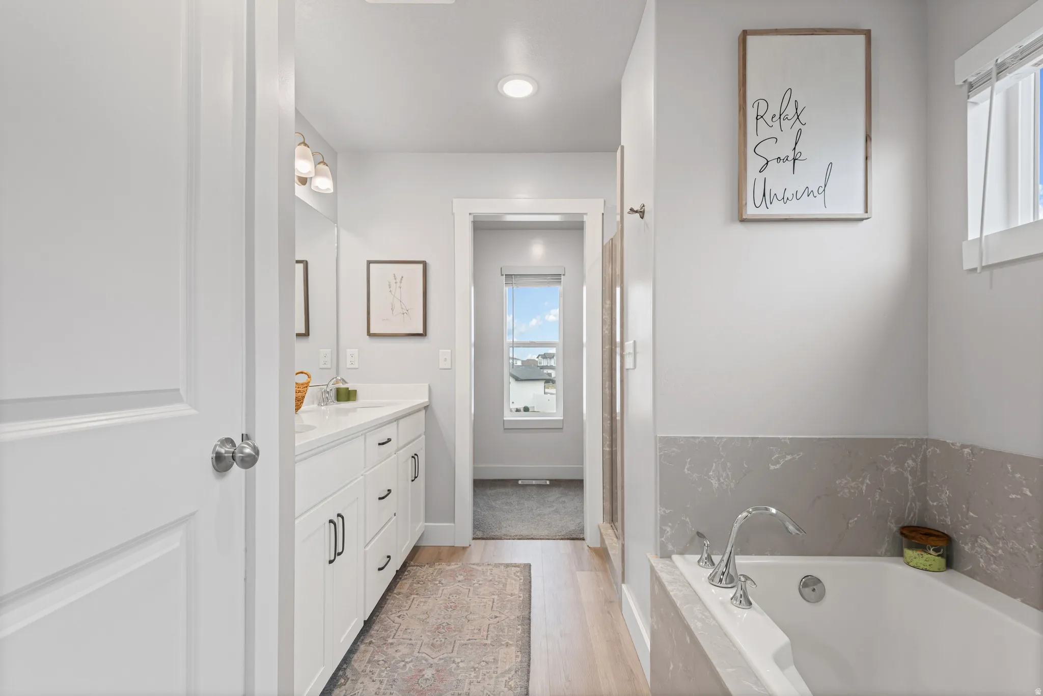 Full bathroom featuring vanity, light wood-style floors, a garden tub, and recessed lighting