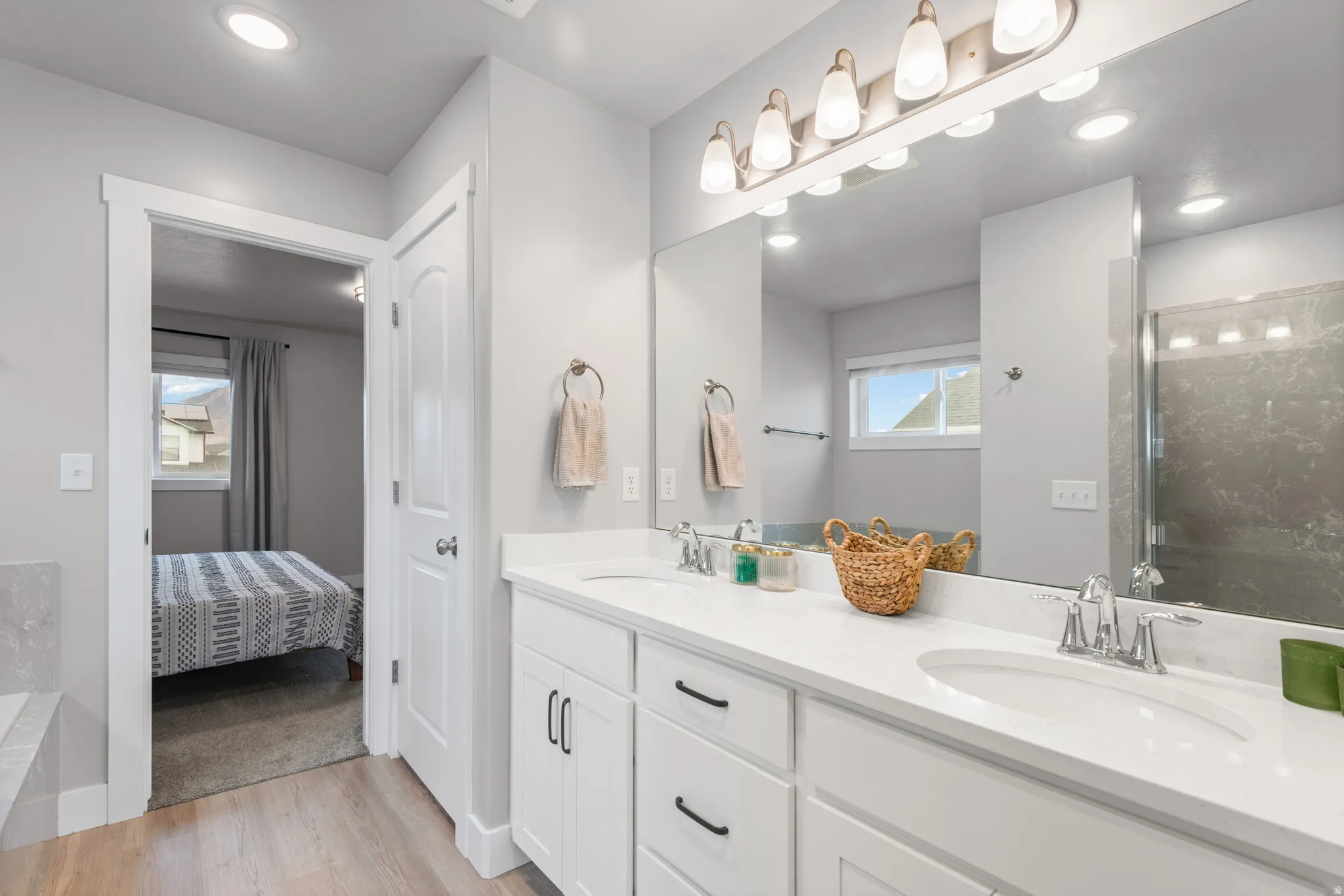 Full bath featuring double vanity, a shower stall, light wood-style floors, recessed lighting, and ensuite bath