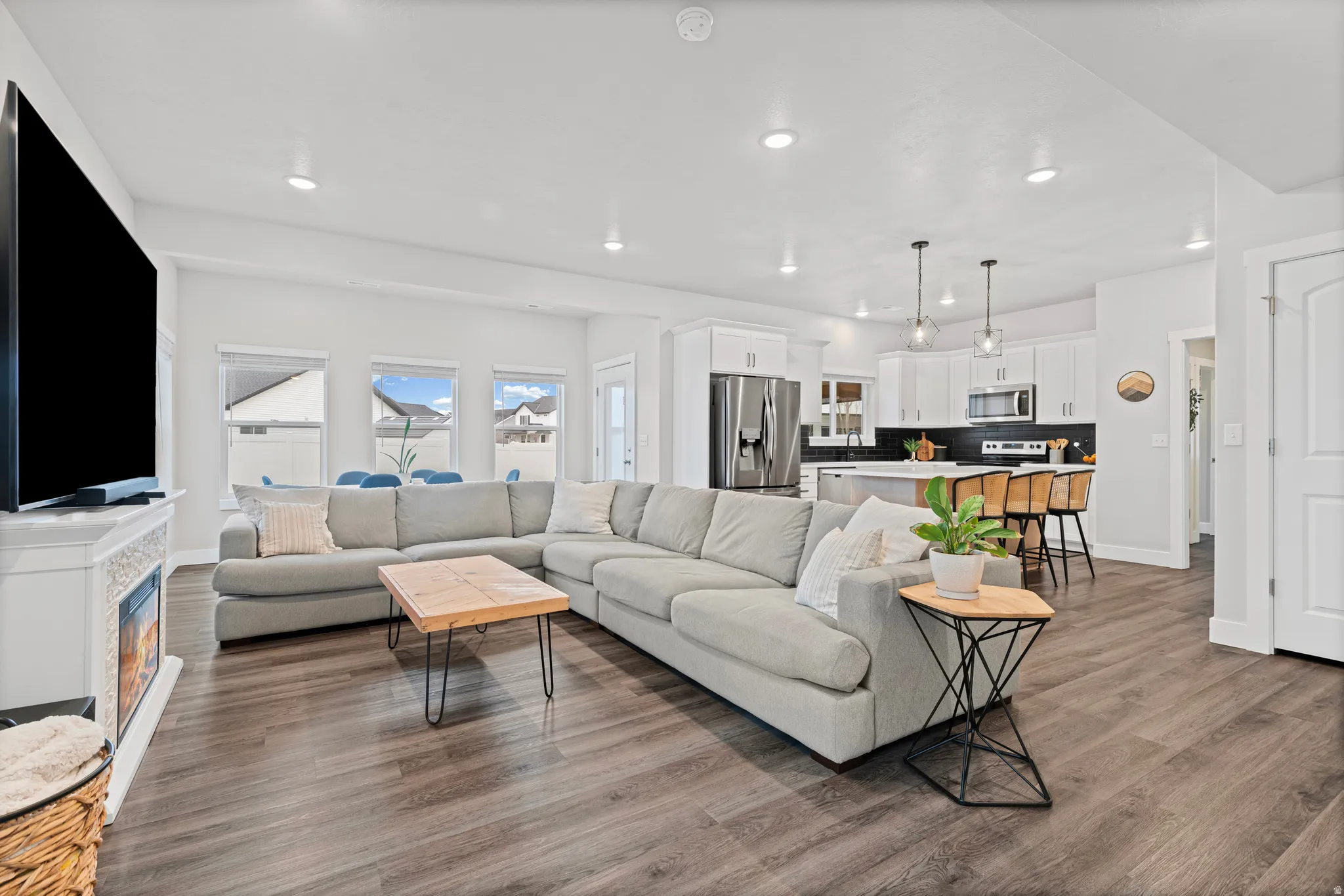 Living area with a glass covered fireplace, dark wood-style floors, and recessed lighting
