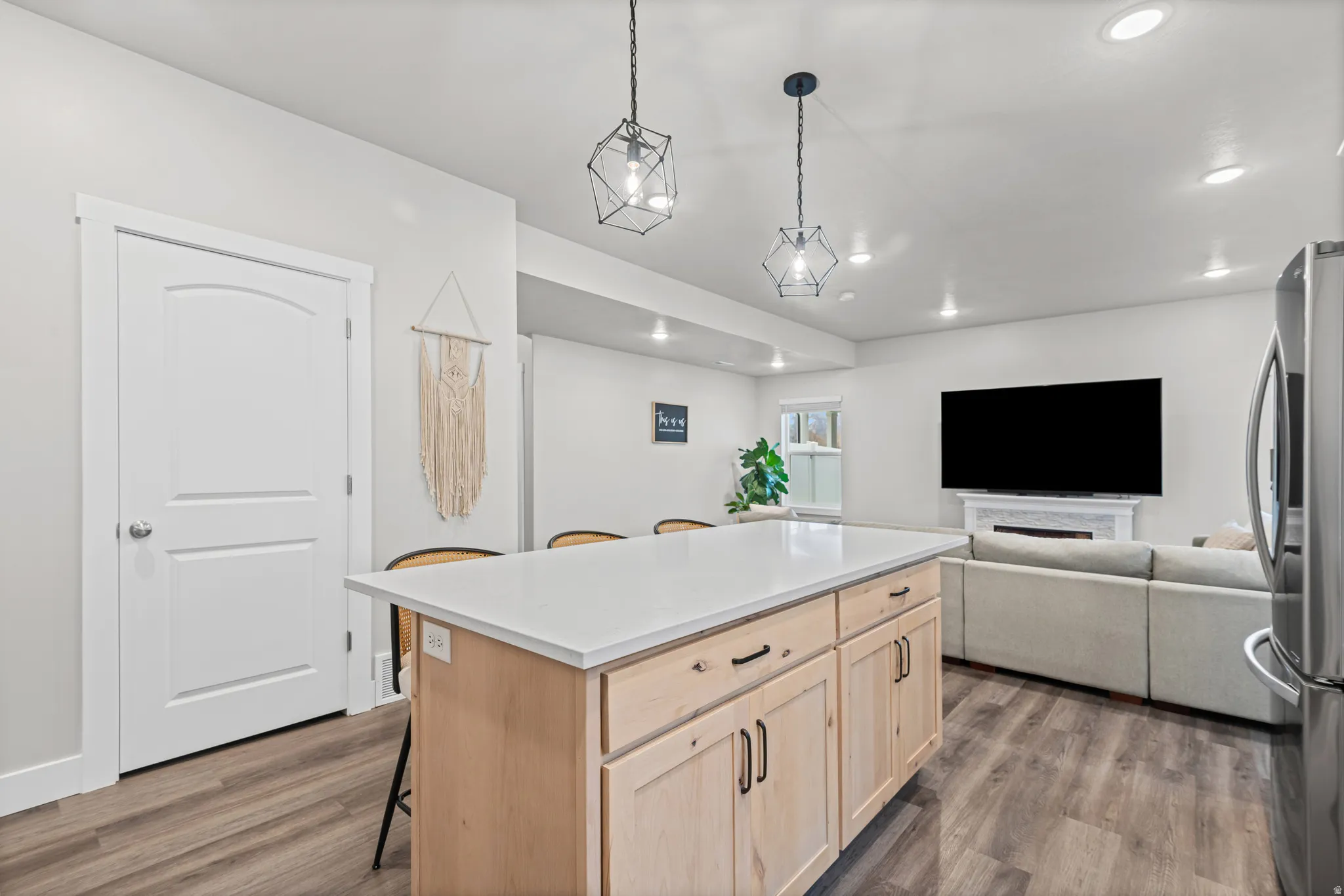 Kitchen featuring light brown cabinetry, a breakfast bar area, open floor plan, a kitchen island, and freestanding refrigerator