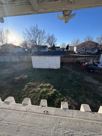 Fenced backyard featuring a residential view and a shed