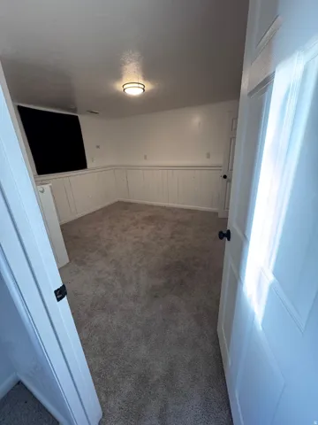 Carpeted spare room with a wainscoted wall