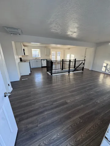 Unfurnished living room with dark wood-style flooring, a textured ceiling, and cooling unit