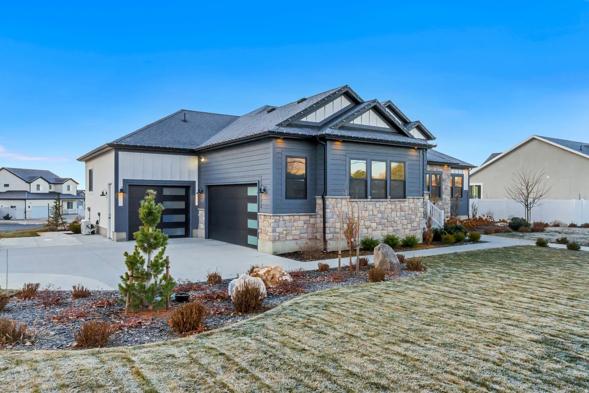 View of front of property featuring board and batten siding, stone siding, concrete driveway, a front yard, and a garage