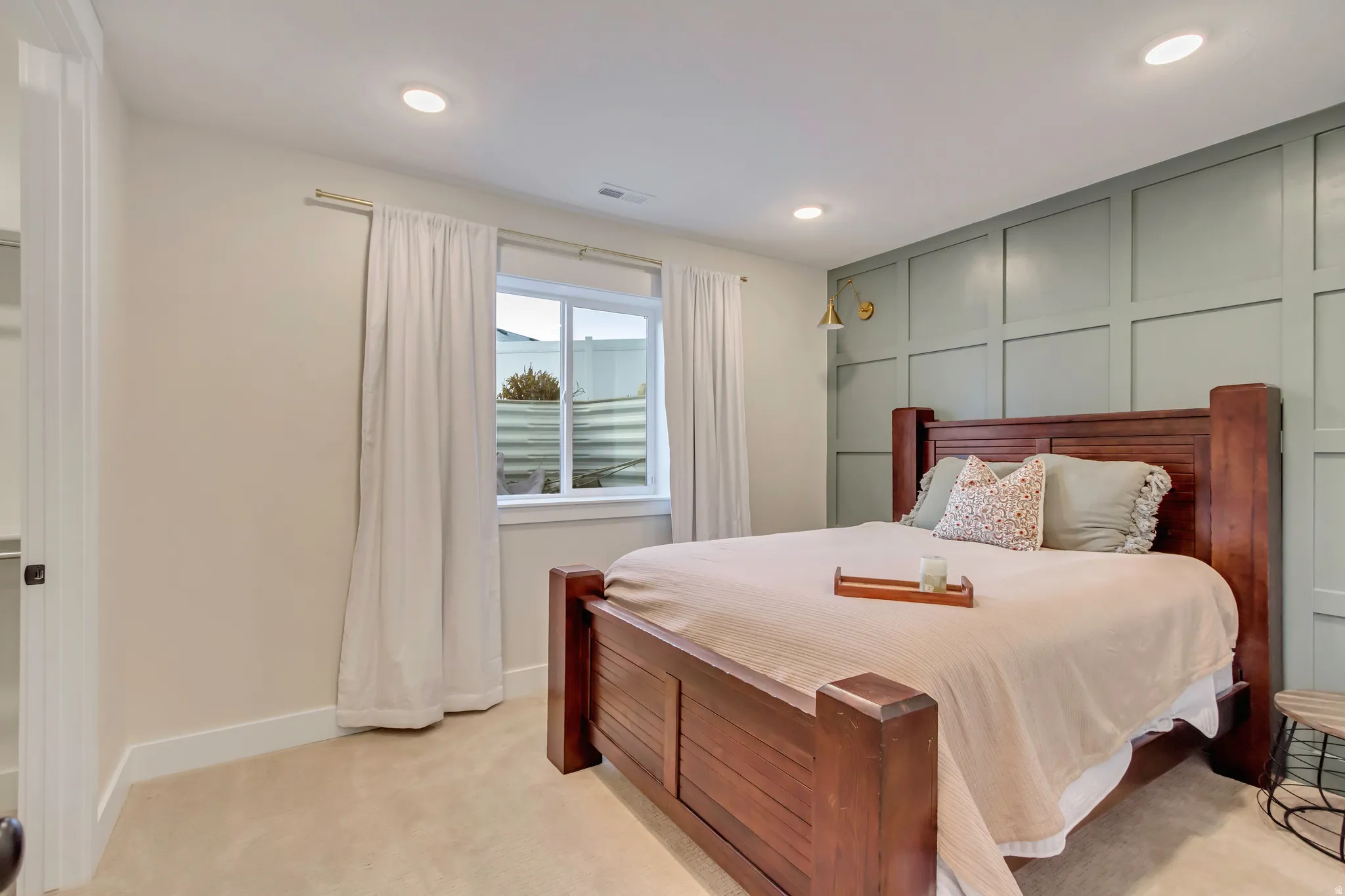 Bedroom featuring light colored carpet, a decorative wall, and recessed lighting