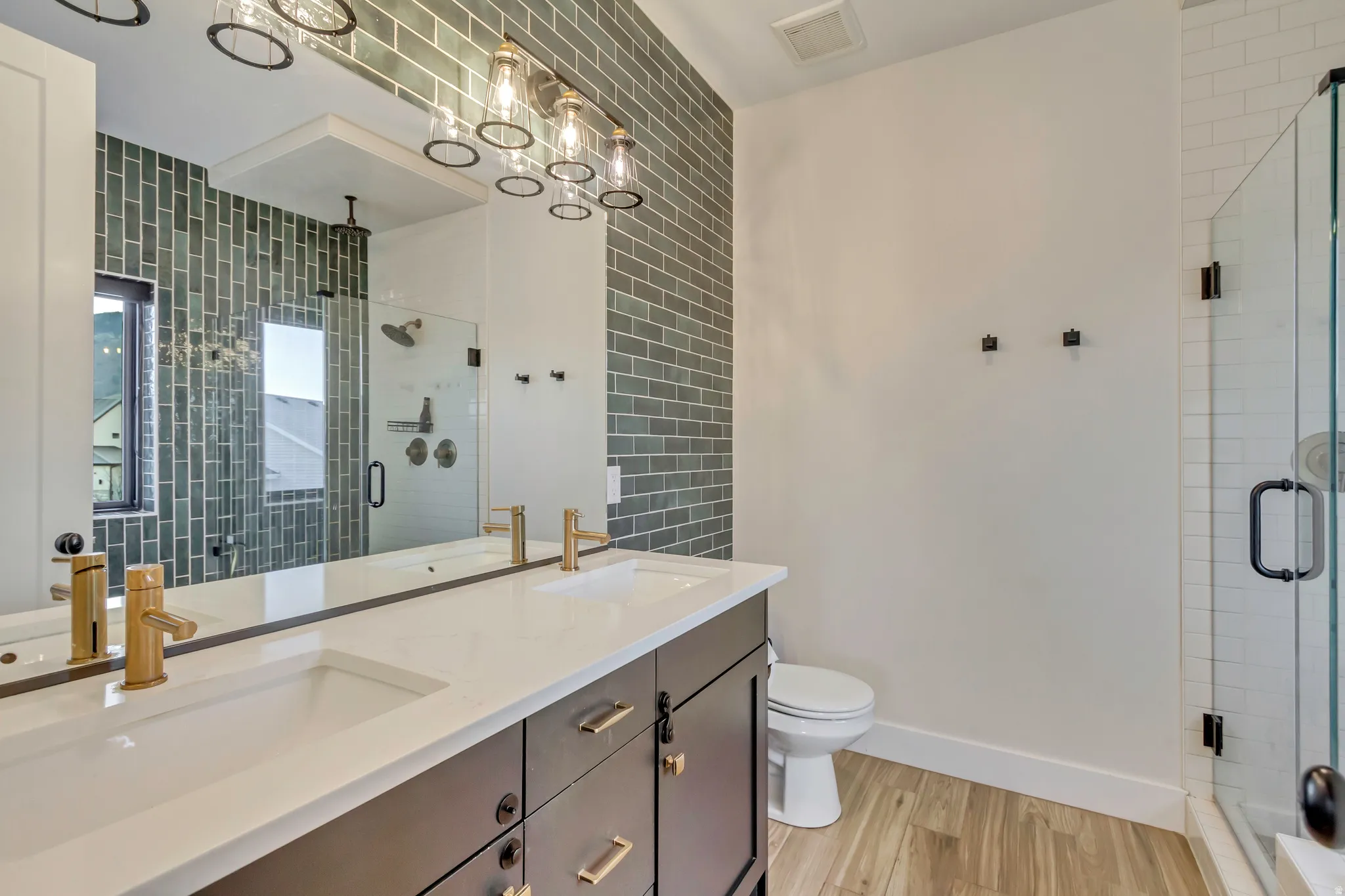 Full bathroom featuring double vanity, light wood-type flooring, and a shower stall