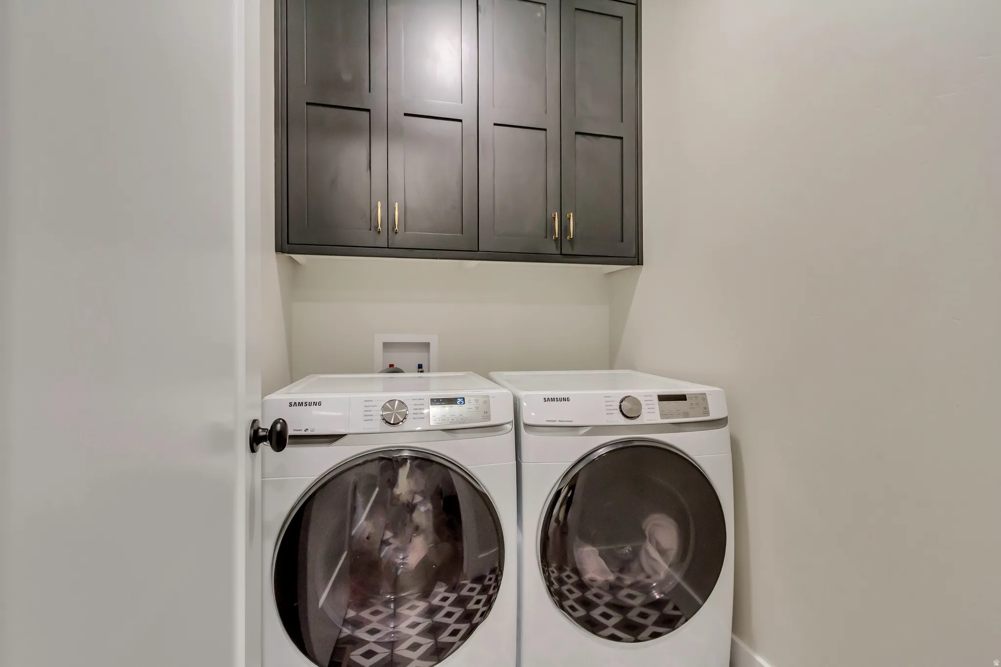 Washroom with cabinet space and washing machine and dryer