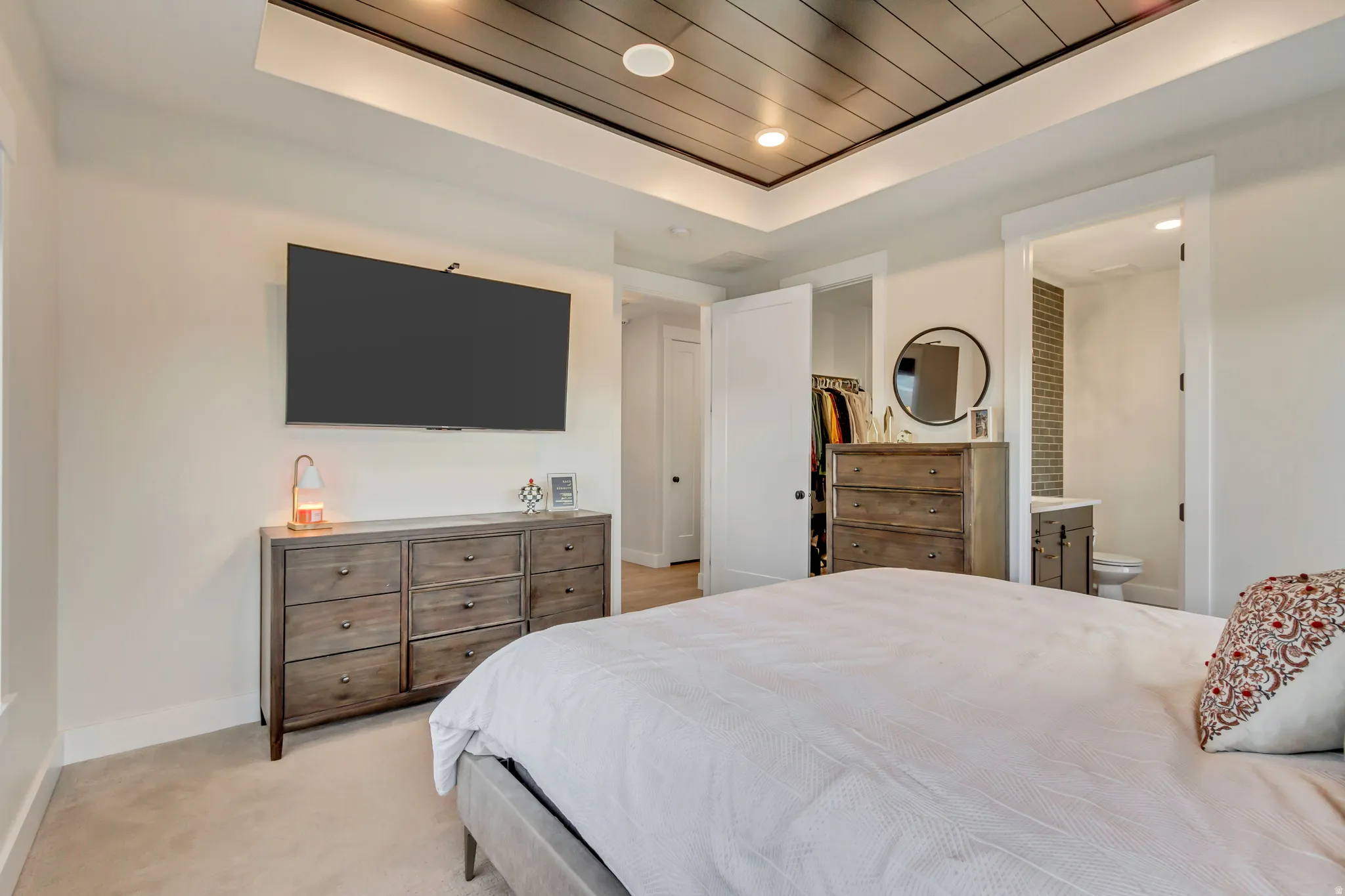 Bedroom with light colored carpet, a spacious closet, recessed lighting, a tray ceiling, and wooden ceiling