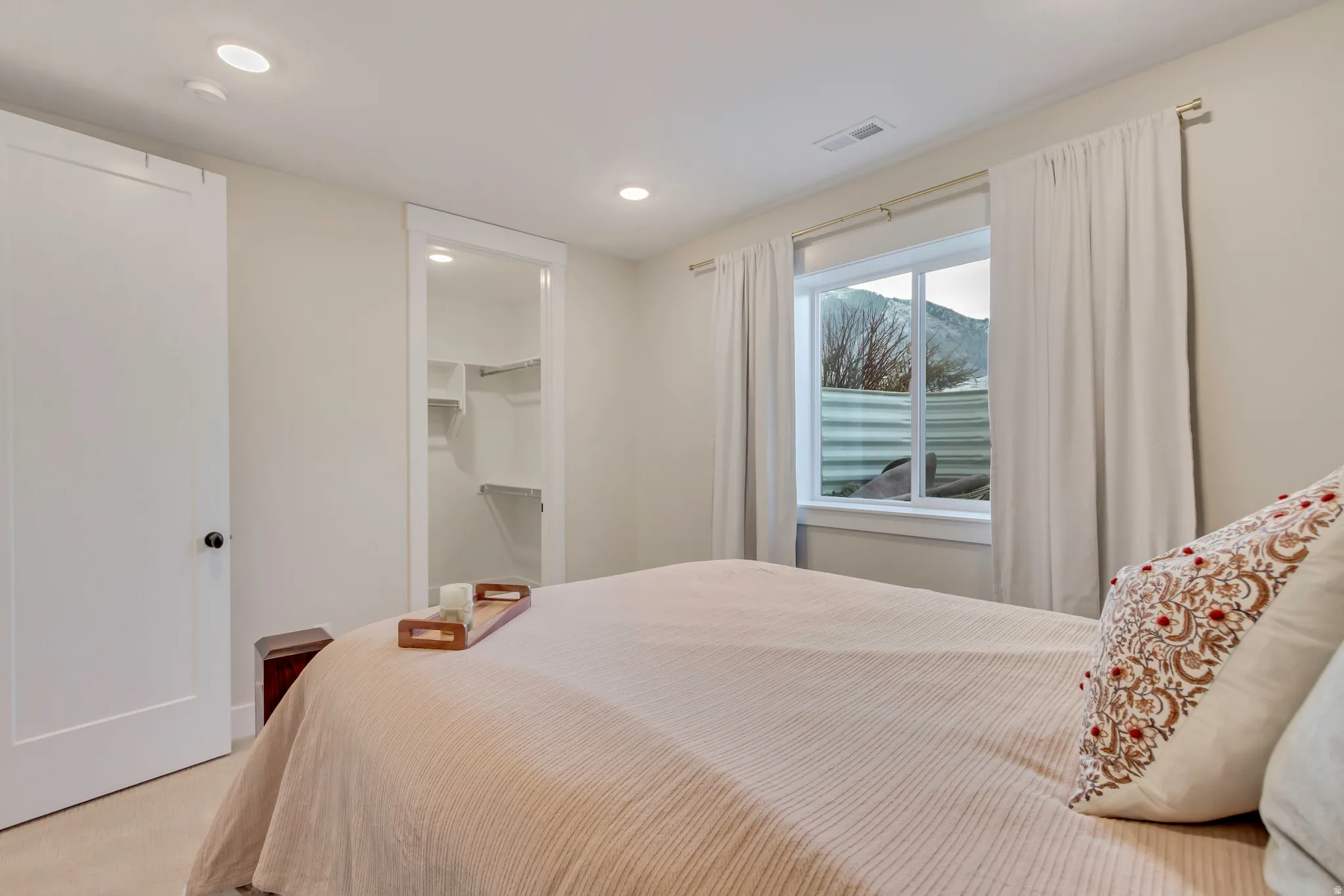 Bedroom with a walk in closet, light colored carpet, and recessed lighting