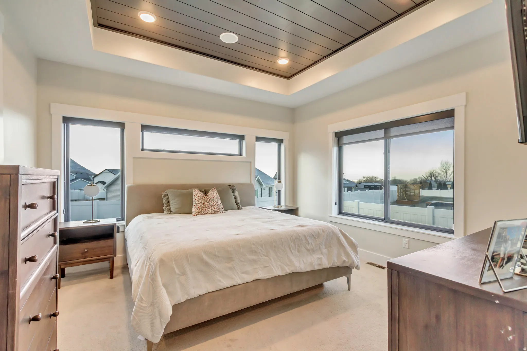 Bedroom with light colored carpet, a tray ceiling, and recessed lighting
