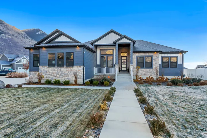 View of front of home with stone siding, a front lawn, and covered porch
