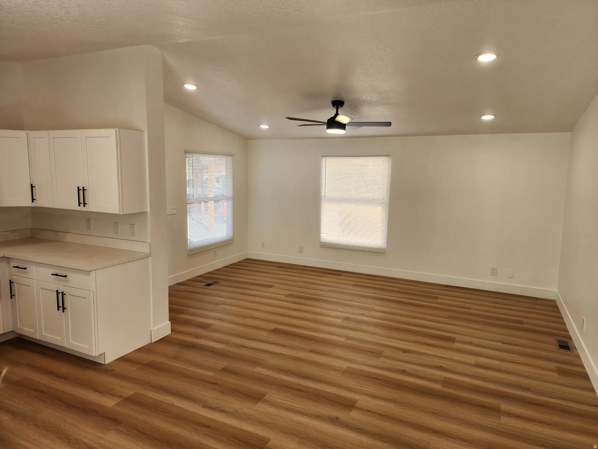 Unfurnished dining area with dark wood-style floors, a ceiling fan, lofted ceiling, and recessed lighting