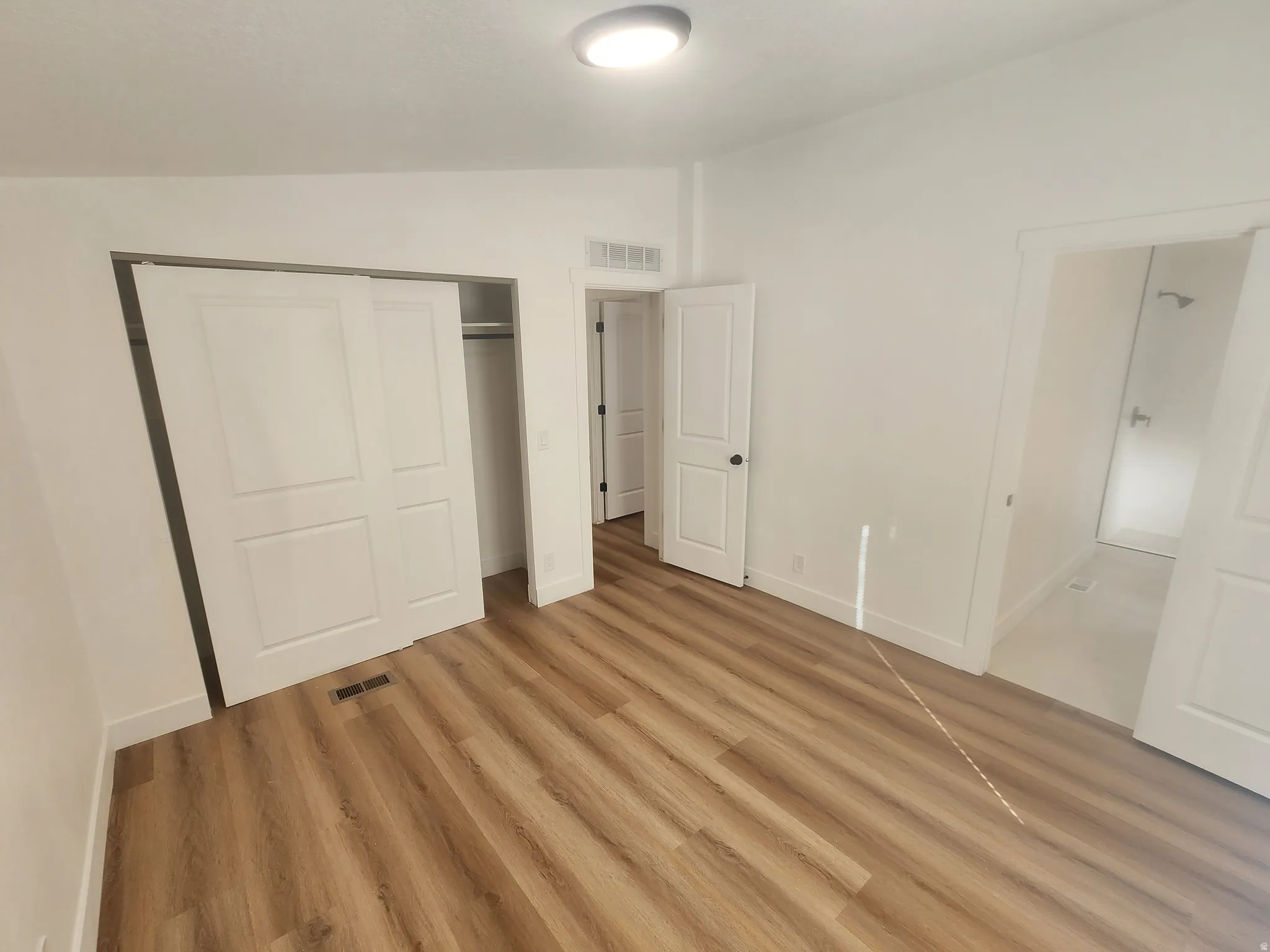 Unfurnished bedroom featuring lofted ceiling, a closet, and light wood-style floors
