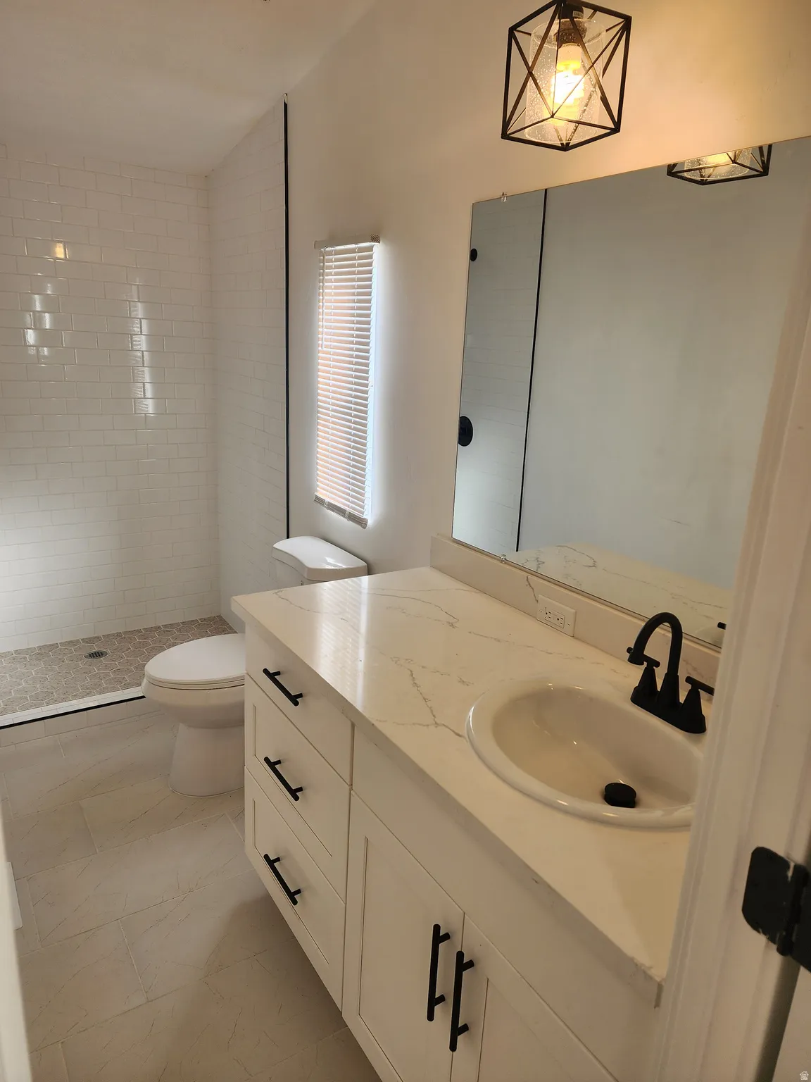Bathroom featuring vanity, tiled shower, and lofted ceiling