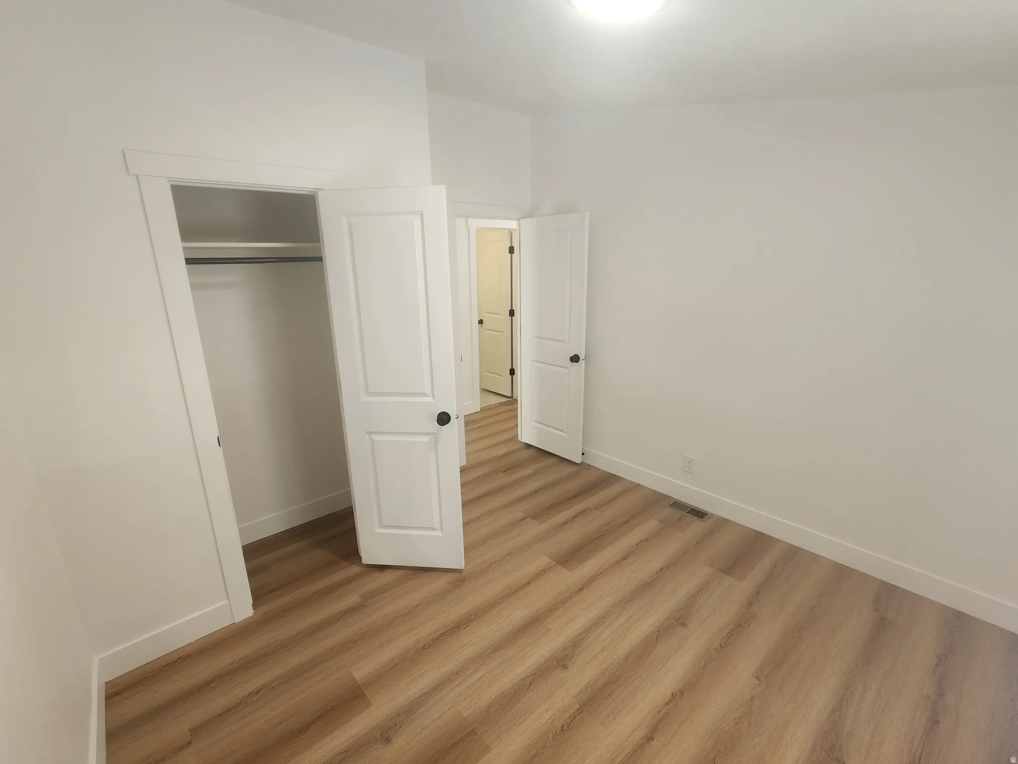 Unfurnished bedroom with light wood-style floors and a closet