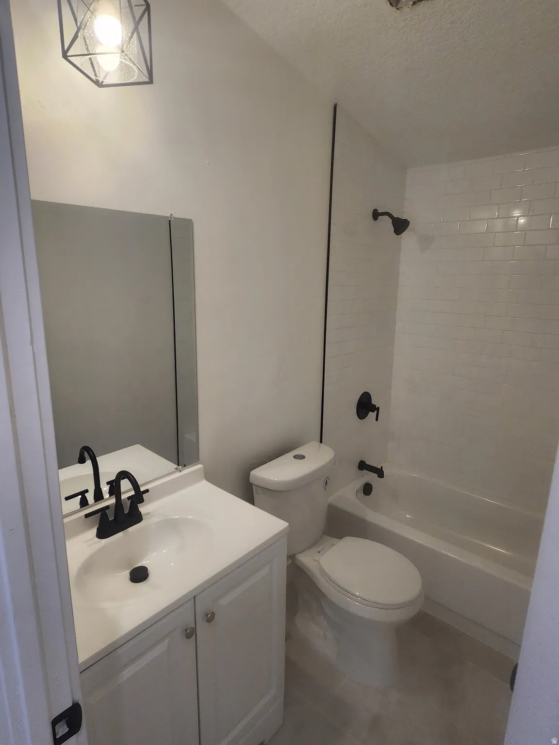 Full bathroom featuring vanity, washtub / shower combination, a textured ceiling, and tile patterned floors