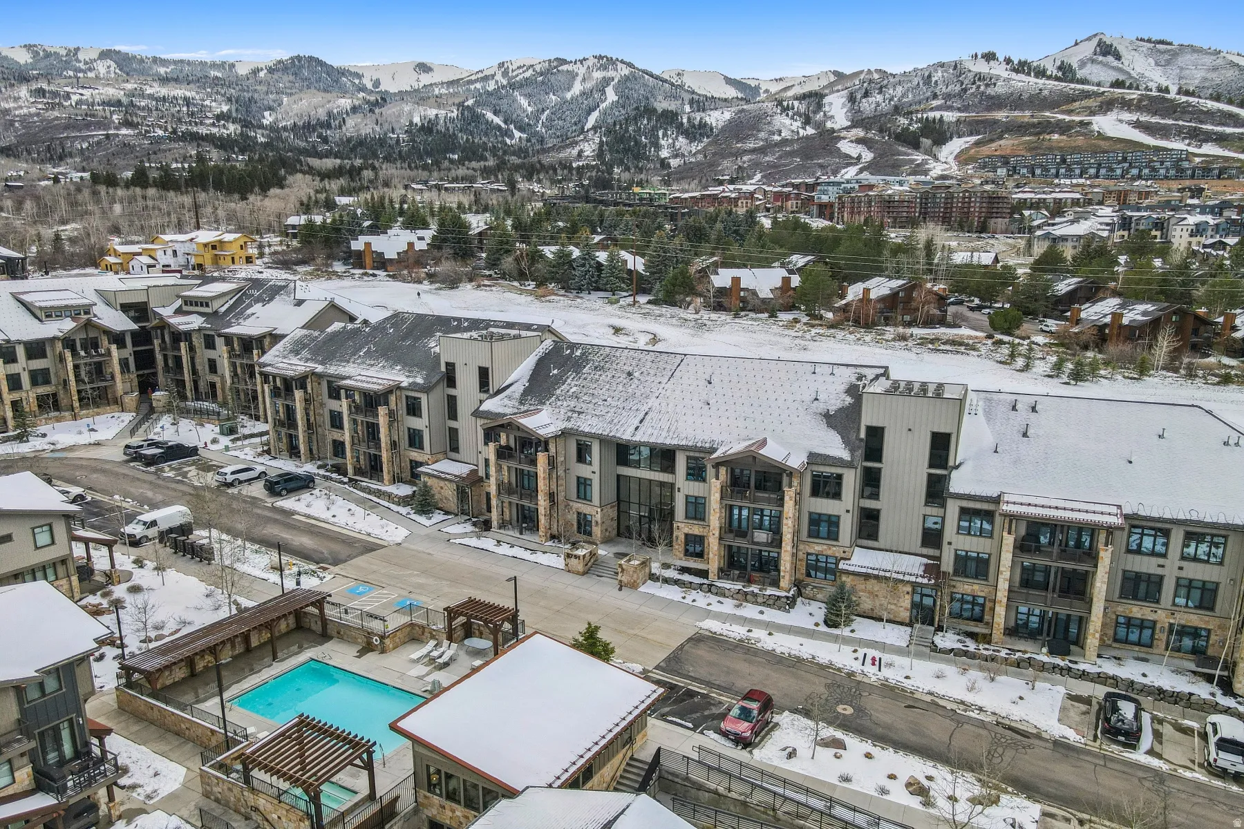 Snowy aerial view featuring a mountain view and view of pool