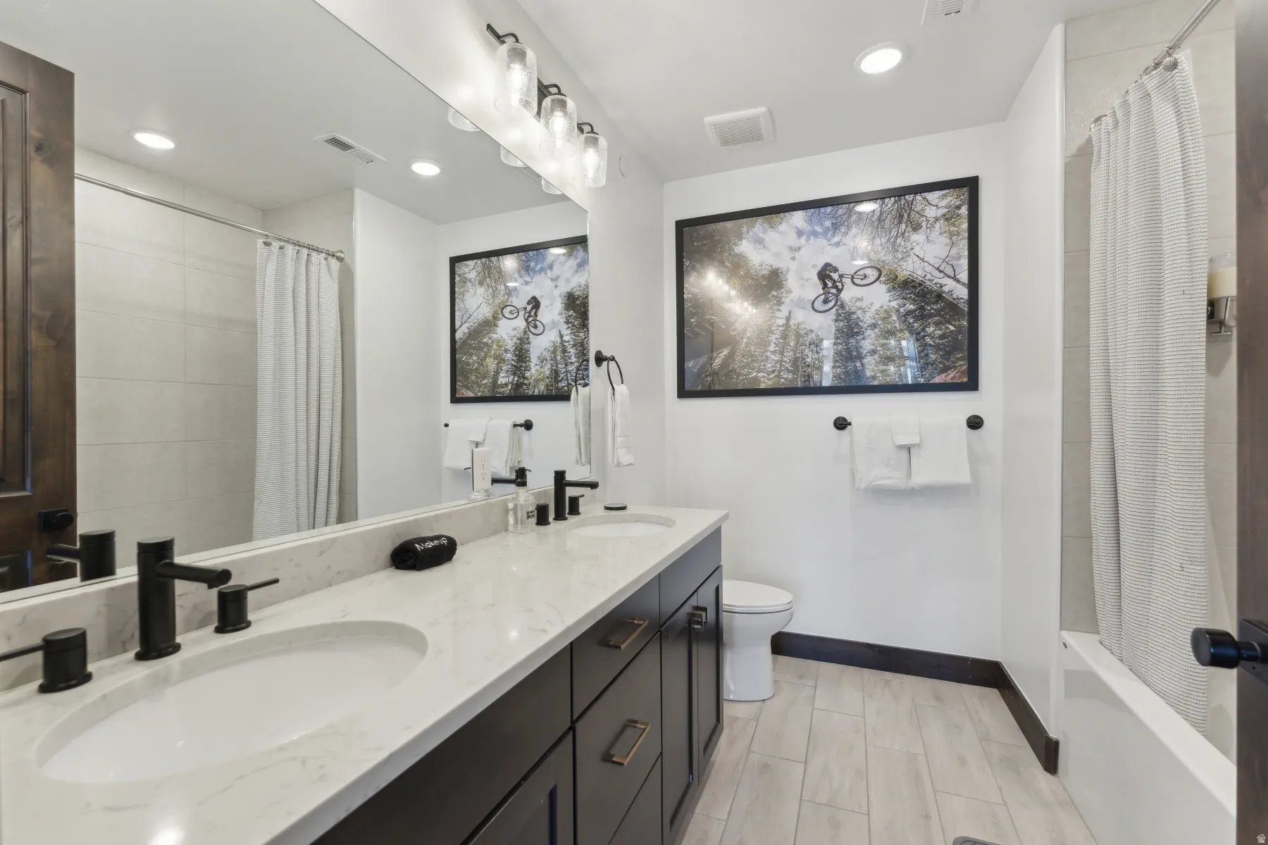 Bathroom with double vanity, recessed lighting, and shower / tub combo with curtain