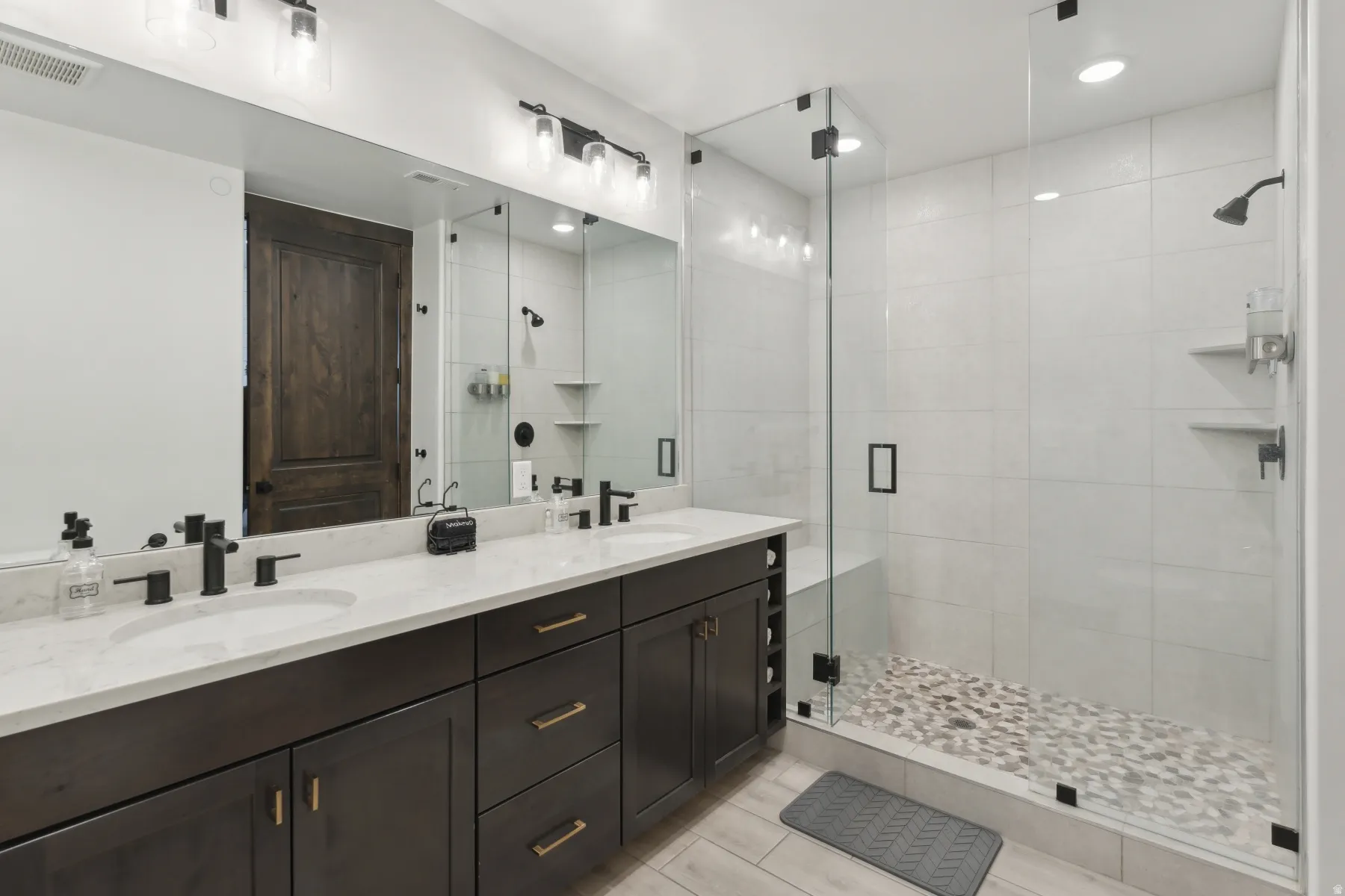 Bathroom featuring double vanity, a stall shower, and recessed lighting