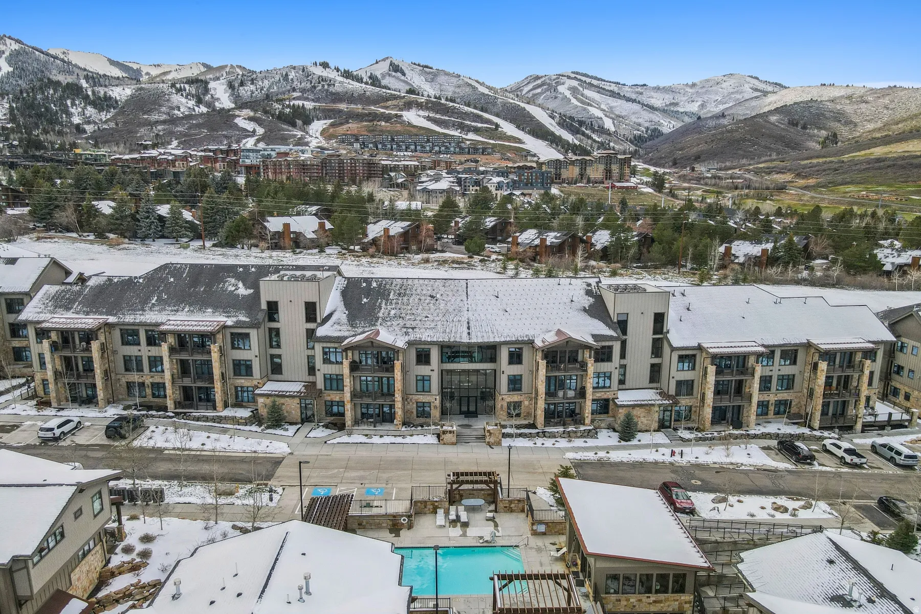 Snowy aerial view with a mountain view and view of pool