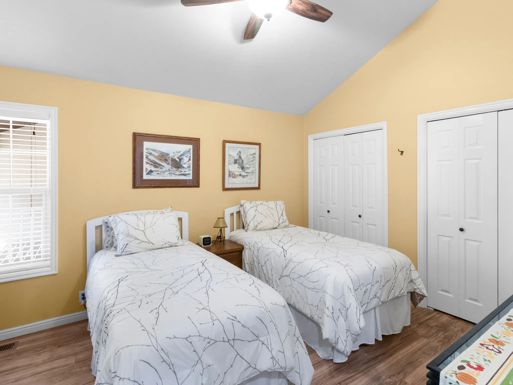 Bedroom featuring multiple closets, vaulted ceiling, dark wood-type flooring, and a ceiling fan
