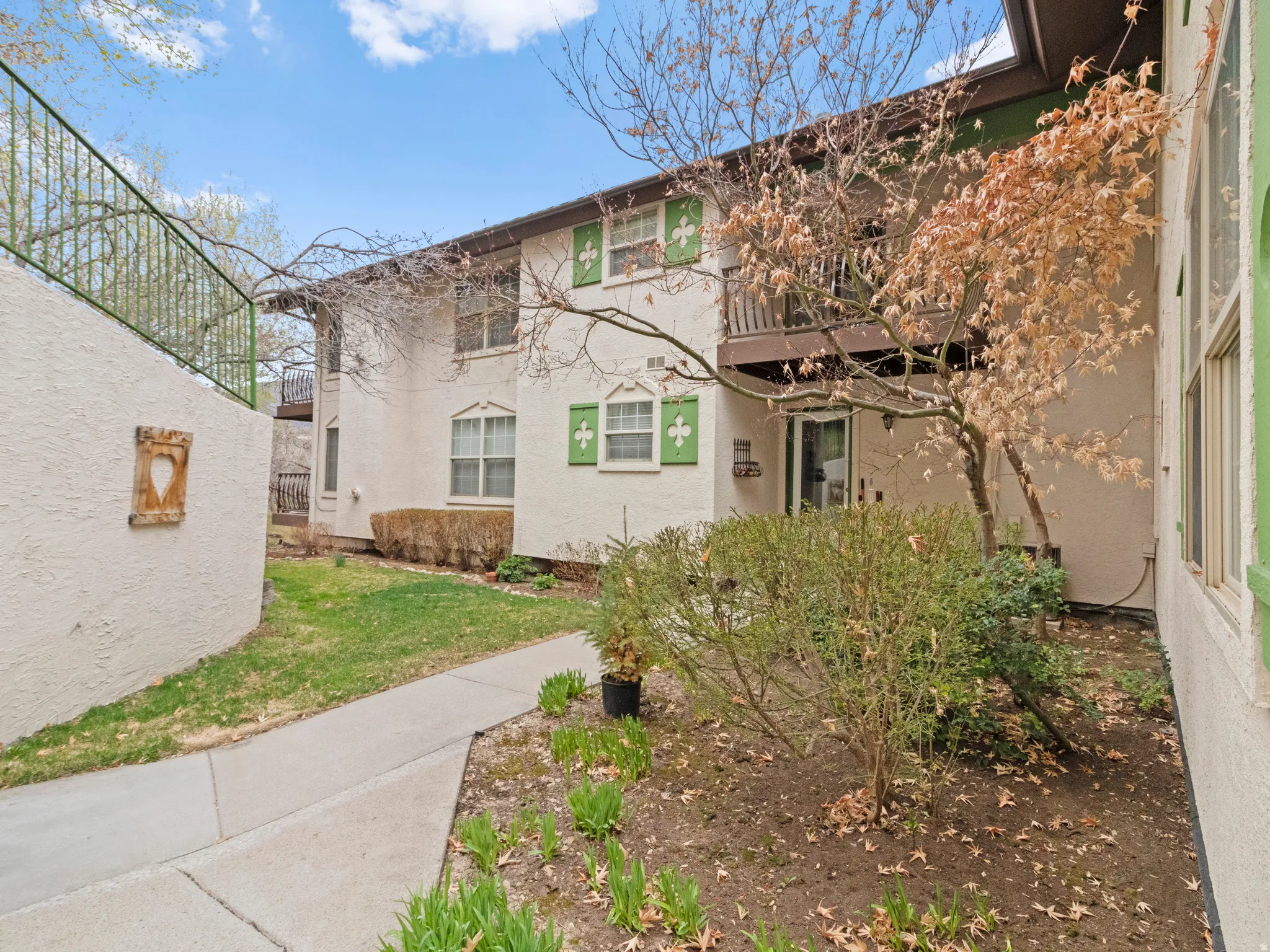 Exterior space featuring stucco siding, a front yard, and a balcony