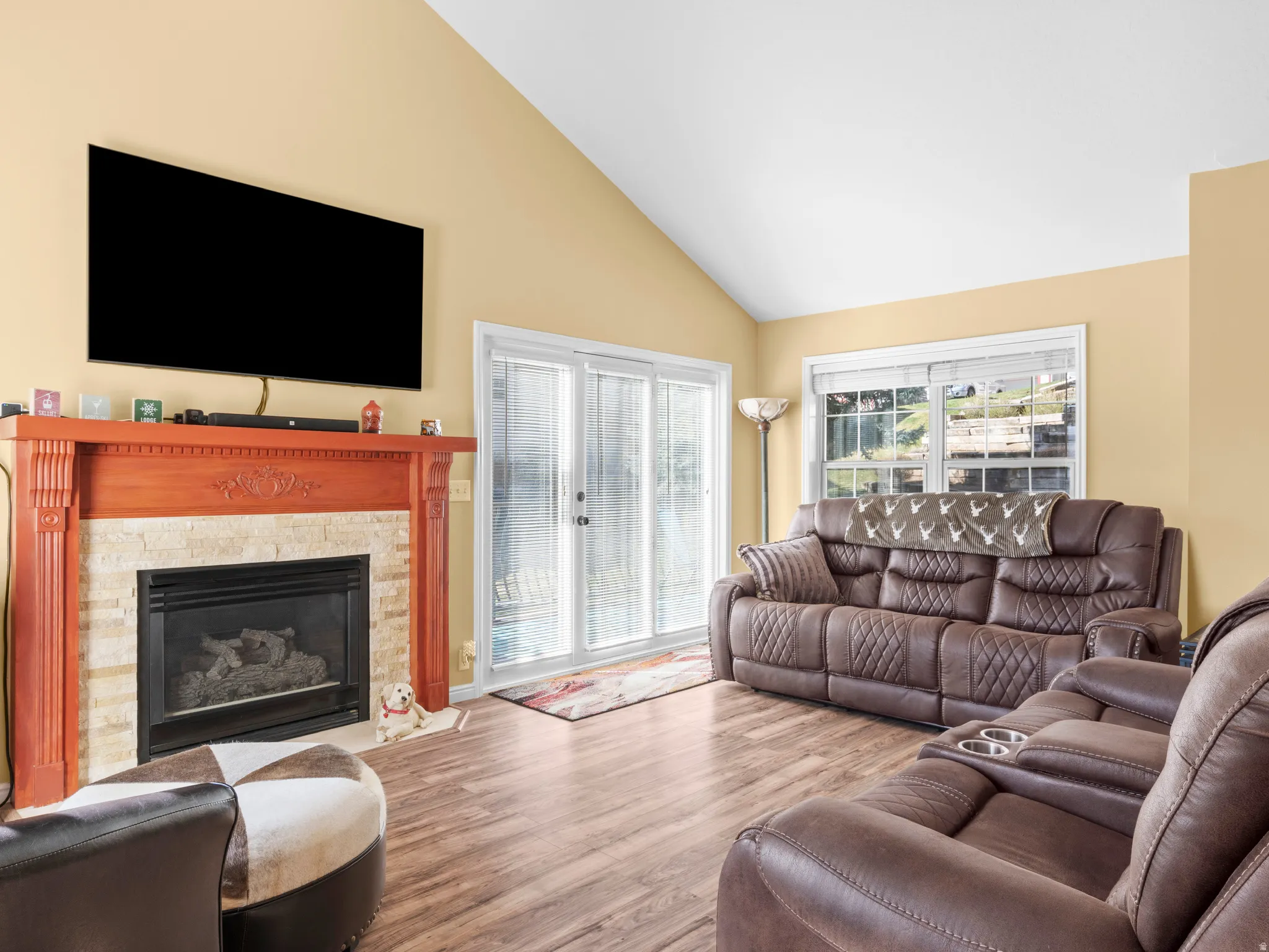 Living area featuring wood finished floors, high vaulted ceiling, and a fireplace