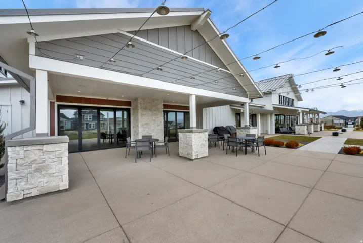 Rear view of house with a patio area, outdoor dining space, board and batten siding, and stone siding