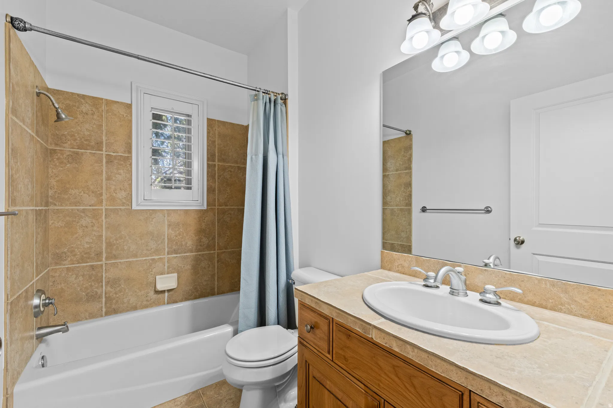 Full bathroom with shower / bath combo with shower curtain, vanity, light tile patterned flooring, and a chandelier