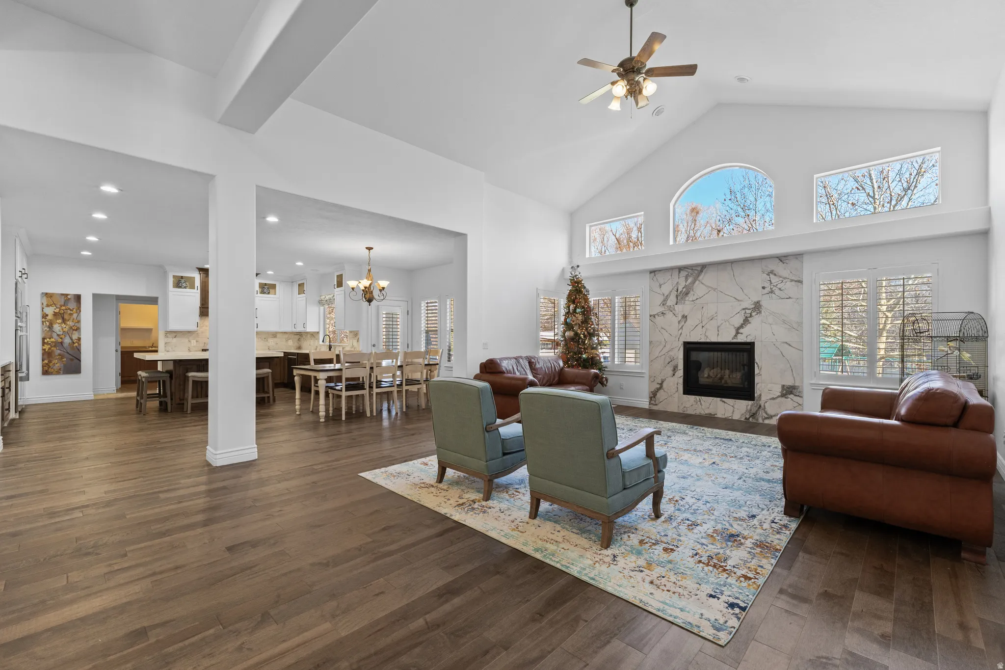 Living room featuring high vaulted ceiling, a high end fireplace, dark wood-style floors, healthy amount of natural light, and recessed lighting