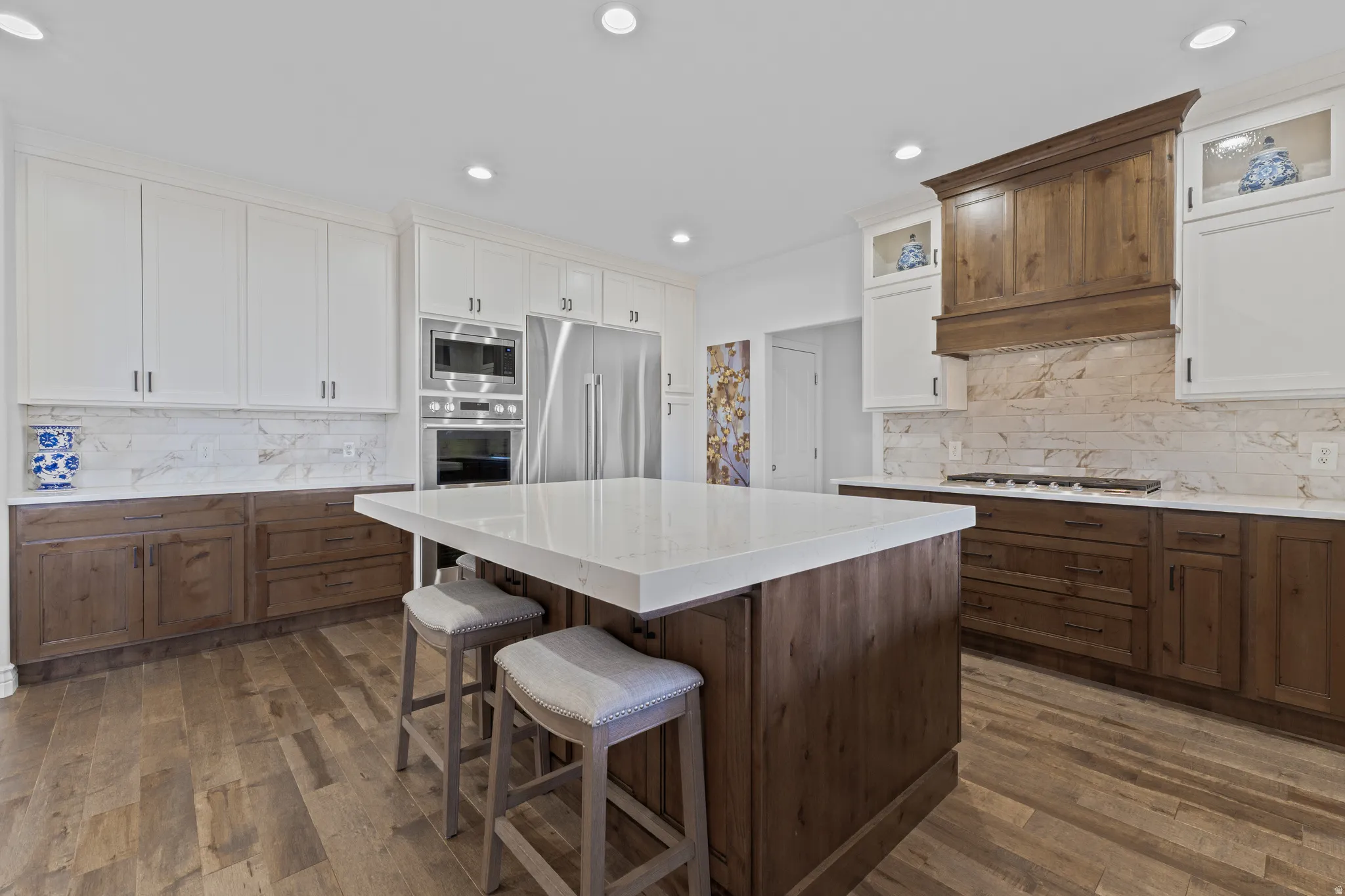 Kitchen with a center island, backsplash, white cabinetry, built in appliances, and dark wood-style floors