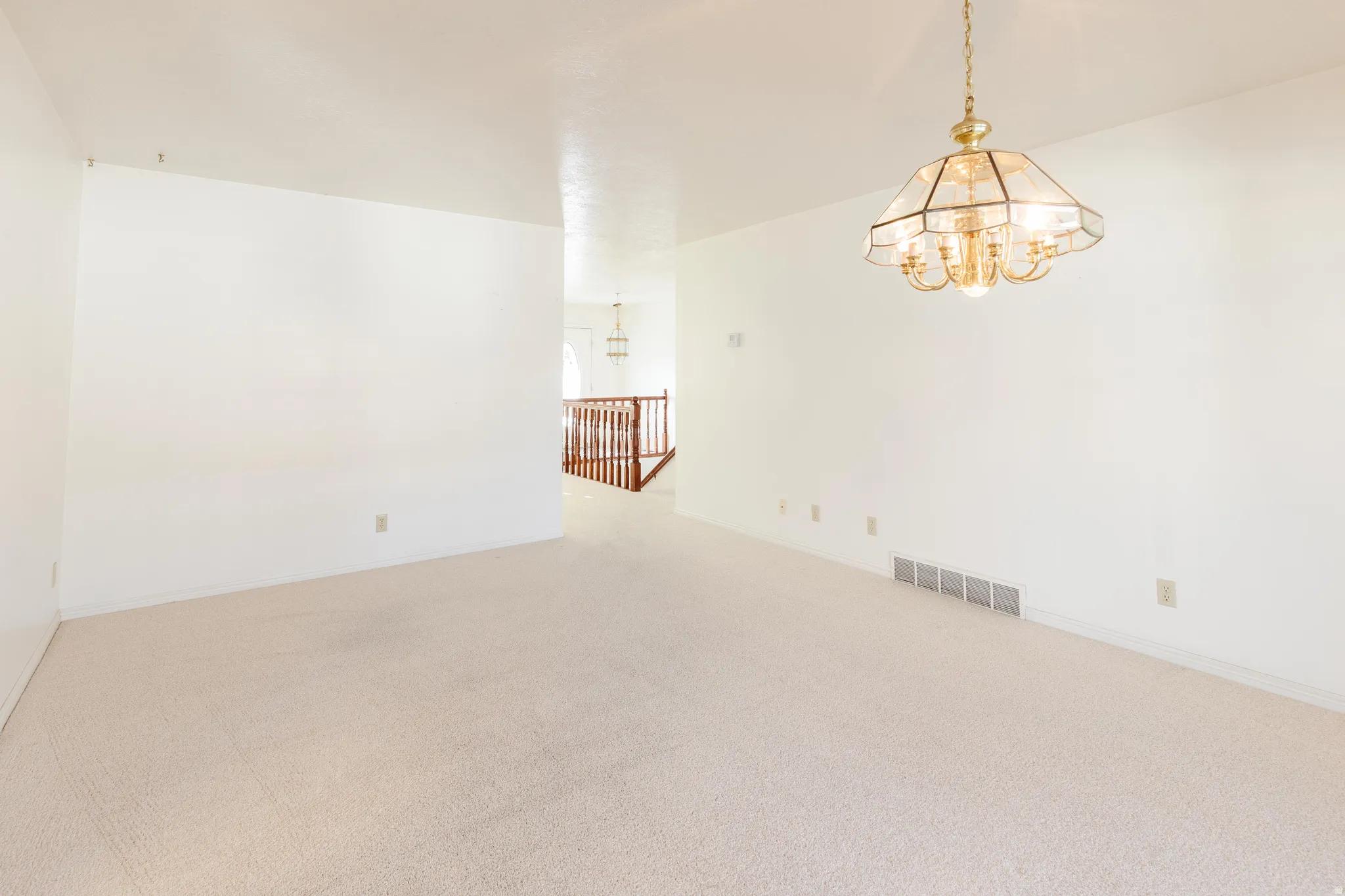 Carpeted spare room featuring a chandelier