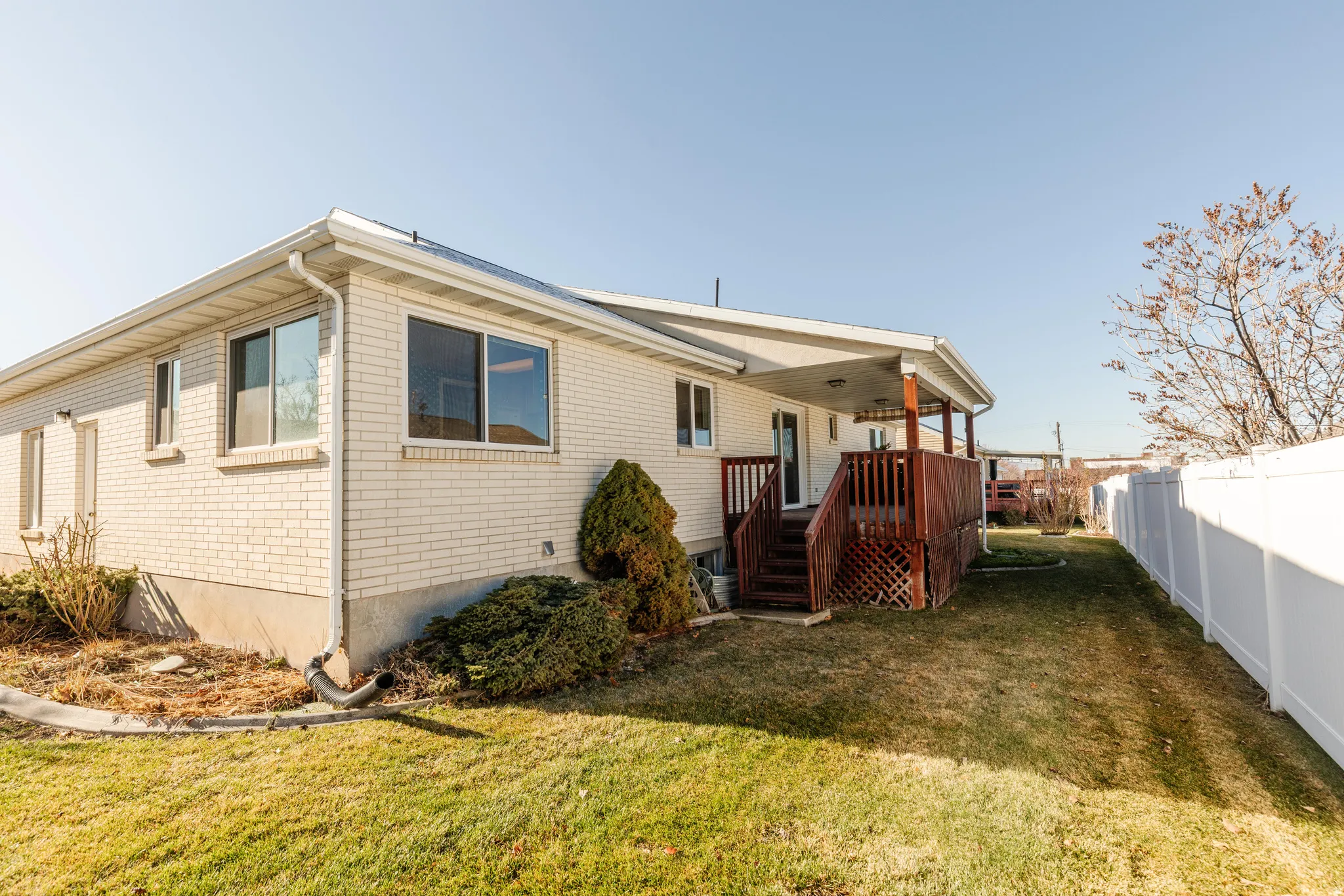 Rear view of house with a fenced backyard, a wooden deck, and brick siding