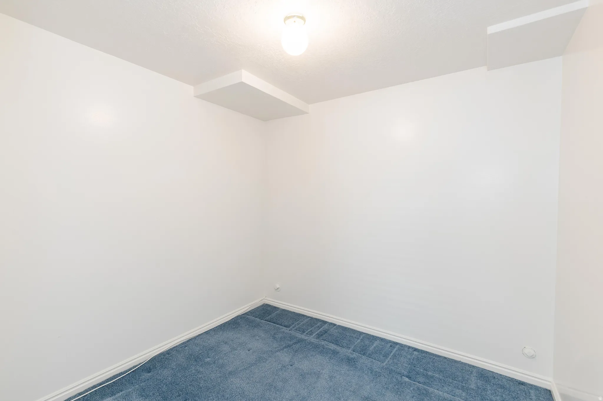 Carpeted spare room featuring baseboards