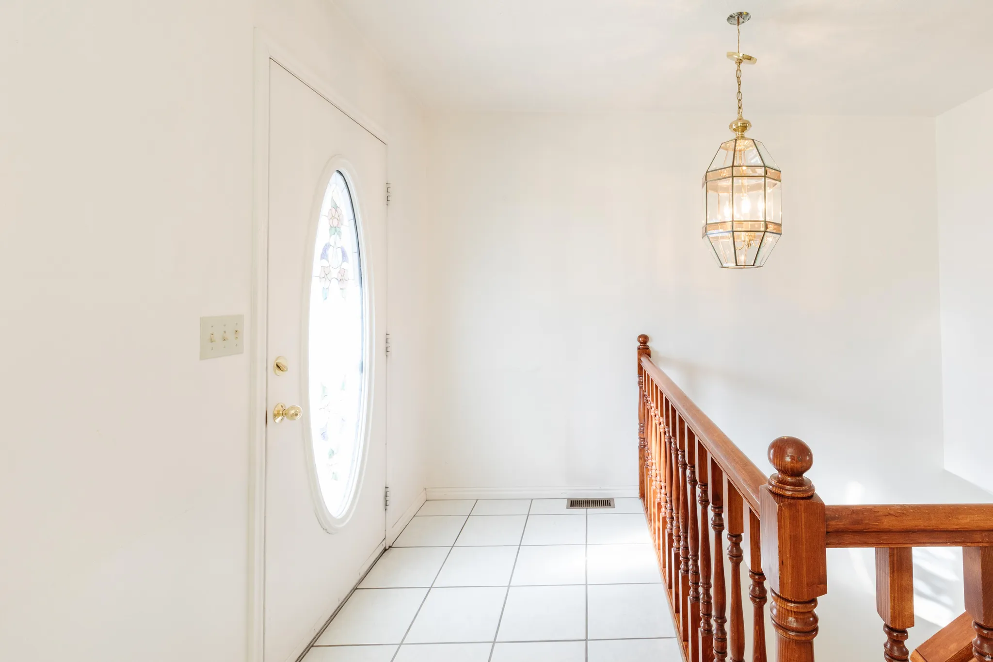 Entryway with light tile patterned flooring and a chandelier