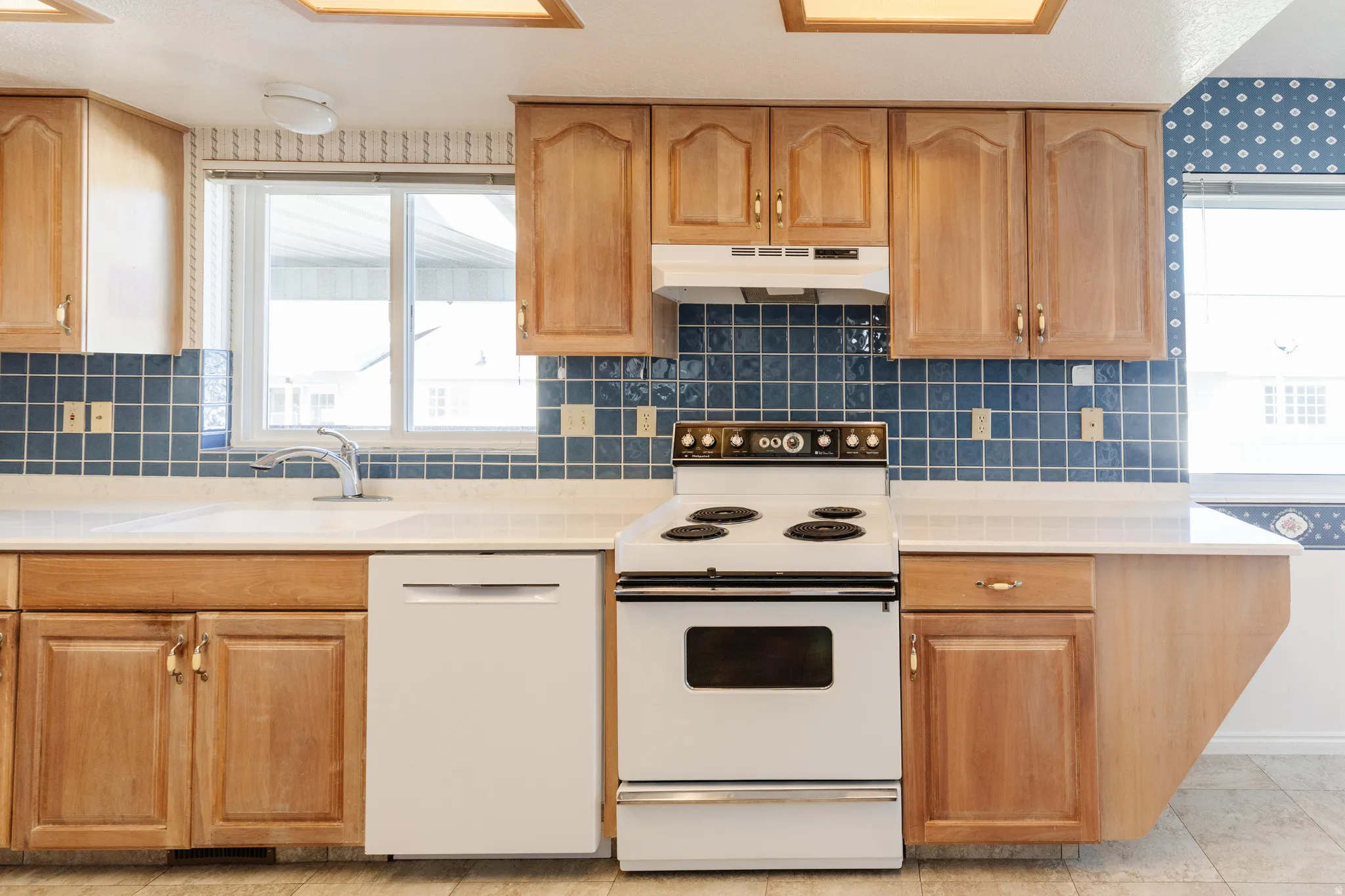 Kitchen featuring white appliances, tasteful backsplash, and healthy amount of natural light
